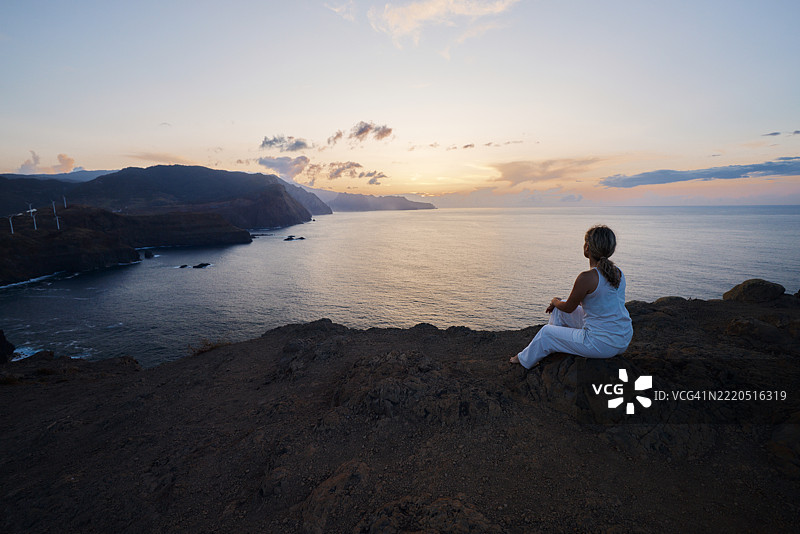 日落时分，运动女性背对着海边悬崖。图片素材
