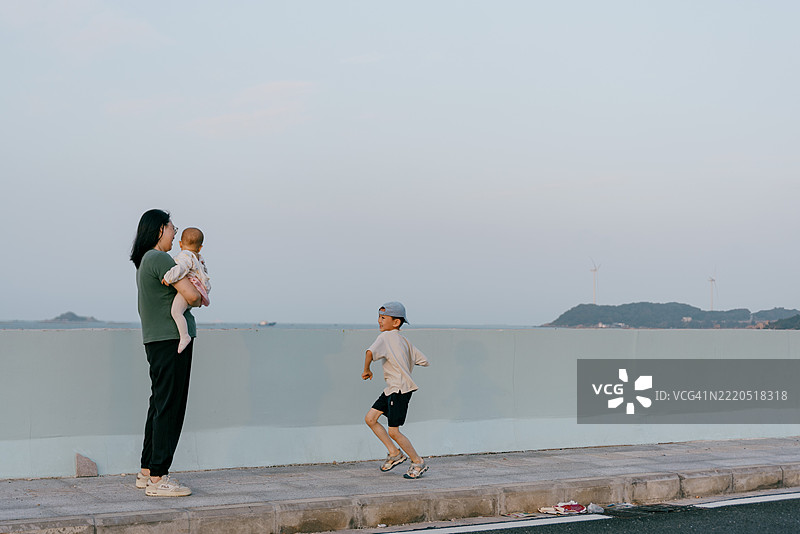 亚洲母亲在海滩上与孩子们玩耍；亚洲家庭生活方式图片素材