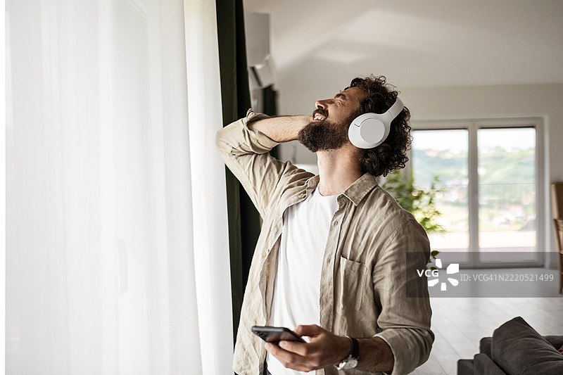 现代男性在自然光下享受音乐和手机时光图片素材