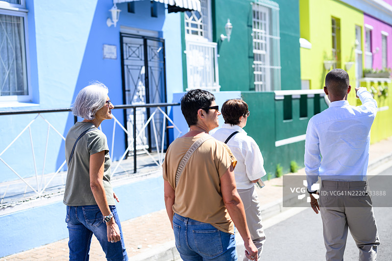 游客在开普敦多彩的博卡普社区与导游一起进行徒步旅行的背影图片素材