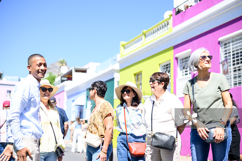 微笑的成熟游客在阳光明媚的博卡普步行游中欣赏色彩斑斓的建筑和房屋图片素材