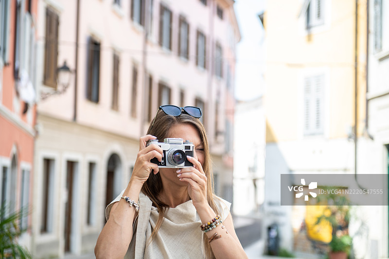 游客女性用复古相机拍摄意大利古城的照片图片素材