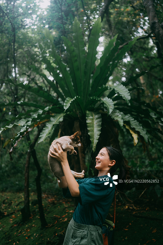 在东京八丈岛的雨林中，快乐的小女孩与狗一起玩耍图片素材