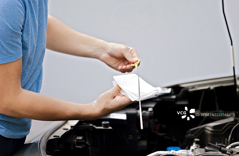 人员检查汽车发动机油以进行例行维护图片素材
