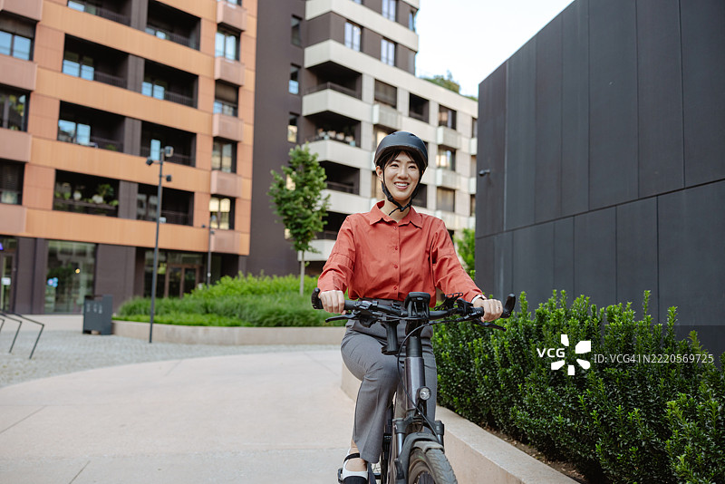 城市骑行的女性佩戴头盔，享受环保的城市生活方式图片素材