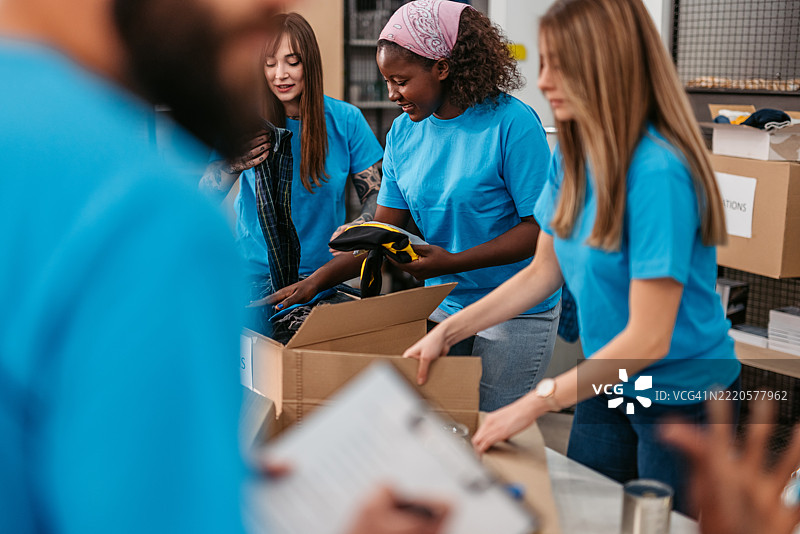 志愿者在捐赠中心将衣物装入捐赠箱中图片素材