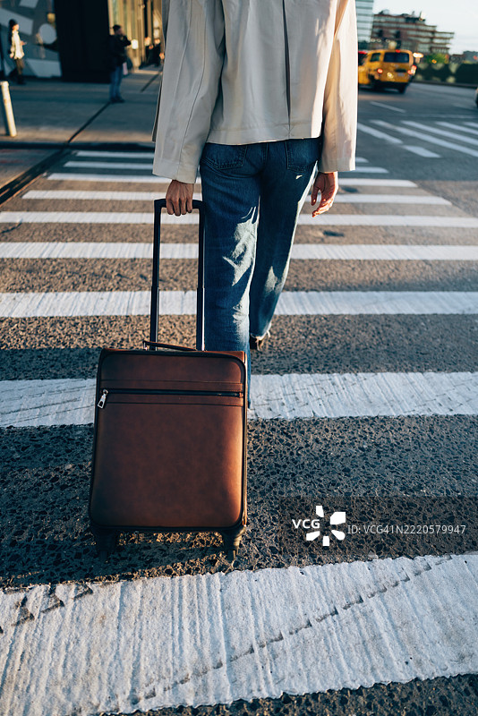 旅客在城市人行横道上拖着时尚的行李箱图片素材