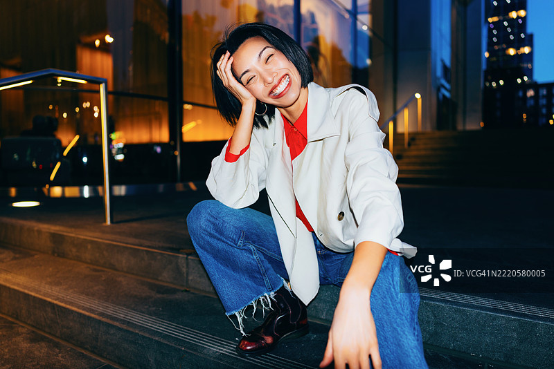 微笑的女性坐在城市户外台阶上的休闲肖像图片素材