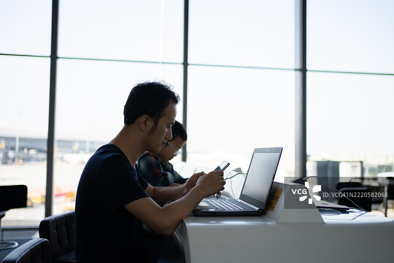一名男子在候机楼内使用笔记本电脑工作图片素材