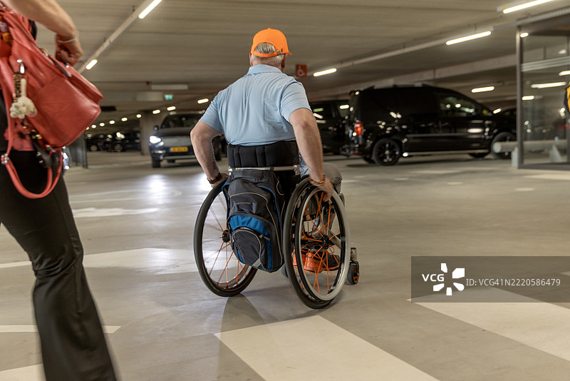 在海滩度假时，帅气的老年轮椅使用者在无障碍停车场。图片素材