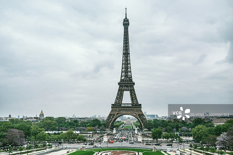 巴黎标志性的埃菲尔铁塔在多云的日子里，周围环绕着绿色植物图片素材