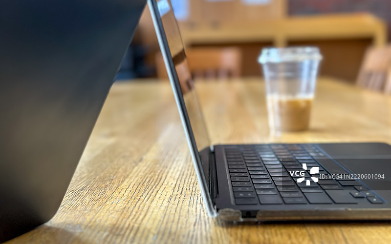 桌子上的笔记本电脑，背景有一杯冰咖啡图片素材
