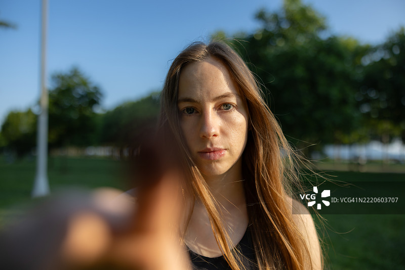 年轻女子在自然中触摸设备屏幕，蓝色眼睛闪烁。图片素材