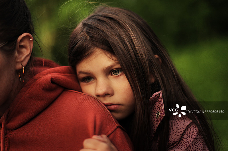 伤心的女儿在户外拥抱母亲，背景是绿色的自然景色图片素材
