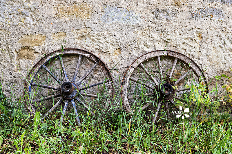 两只旧木轮挂在一面老墙上图片素材
