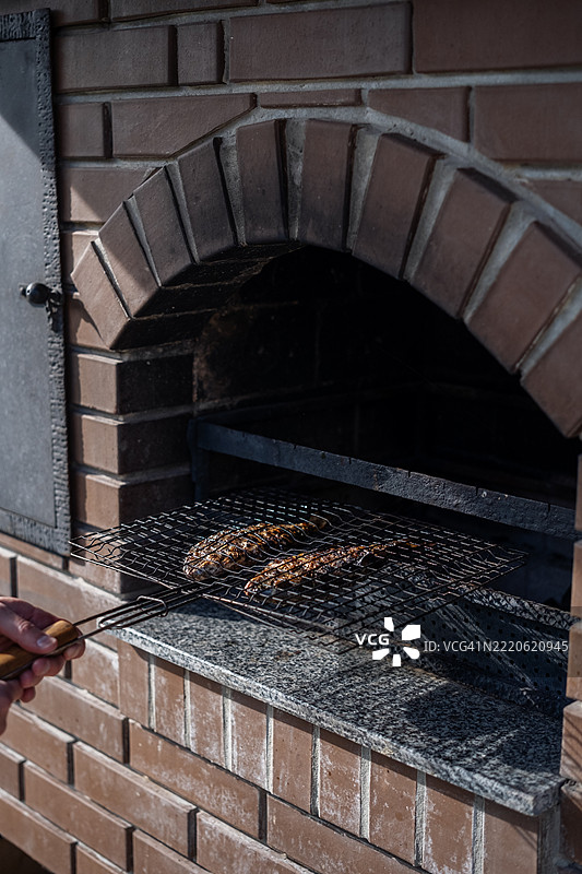 在阳光明媚的下午，户外砖砌烧烤架上烤鱼图片素材