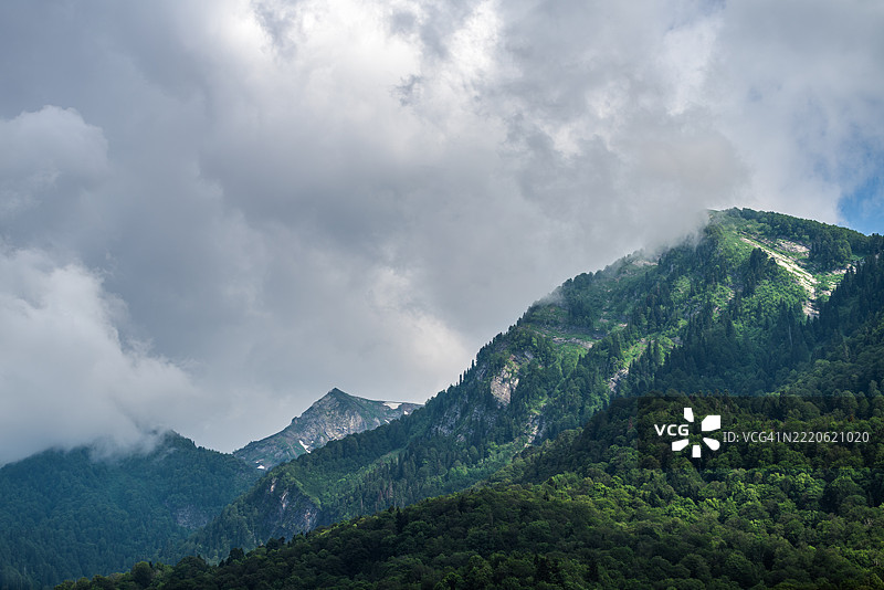 阴云密布的天空覆盖着绿色的山脉和森林图片素材