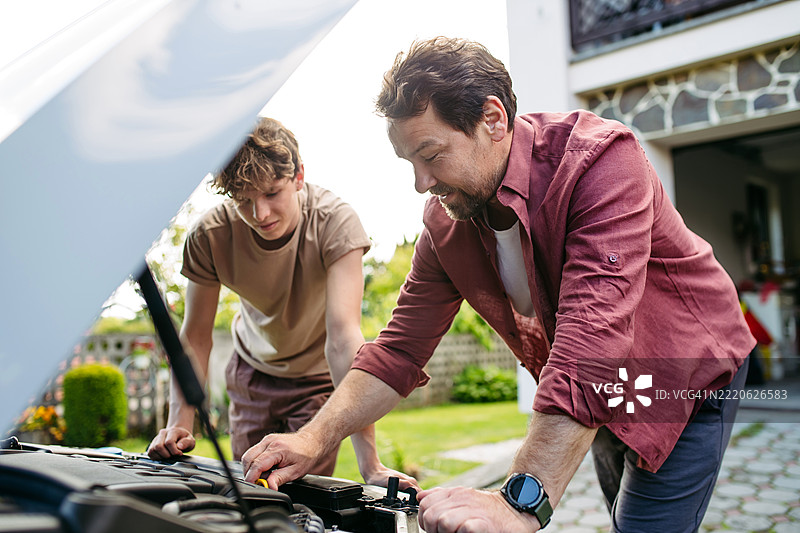 父亲教青少年儿子如何修理汽车。图片素材