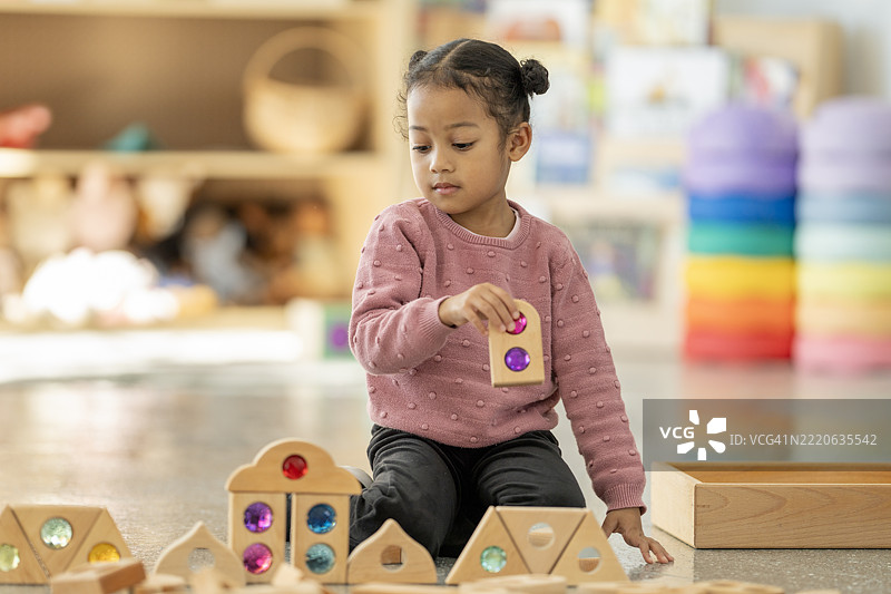 小女孩在托儿所与木制和彩色玩具进行创意游戏图片素材