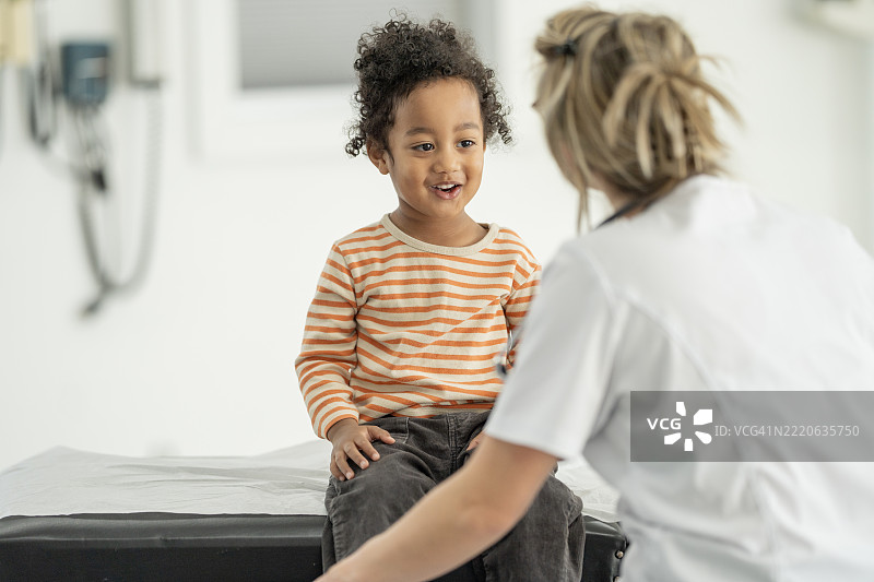 孩子在明亮现代的诊所接受医疗专业人员的照顾图片素材