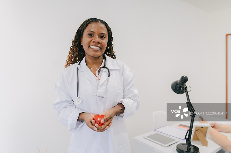 年轻医生手持红色心形符号图片素材