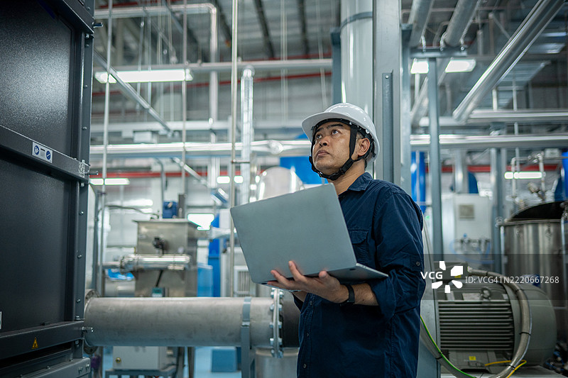 工程师或技术人员在处理大型金属管道、暖通空调系统和工业设备，暗示着一个受控且维护良好的环境概念。图片素材