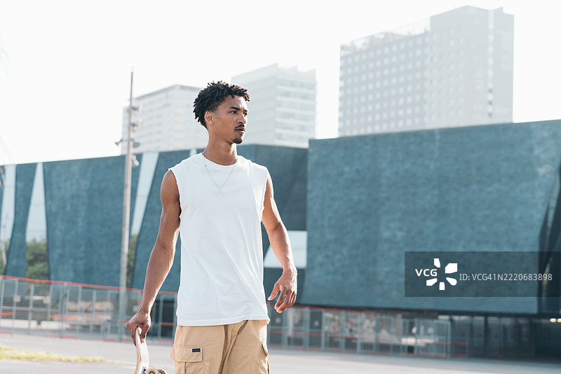 年轻的滑板少年在巴塞罗那的城市环境中行走图片素材