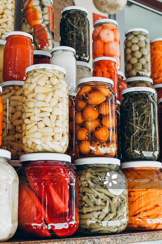 市场桌子上玻璃罐中的罐装蔬菜特写。自制蔬菜腌制品。图片素材