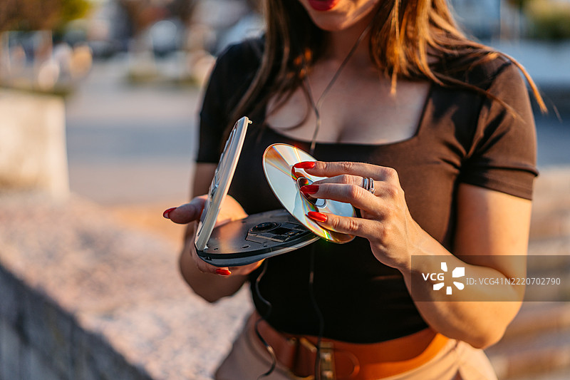 年轻女性在码头边将CD放入便携式CD播放器中图片素材