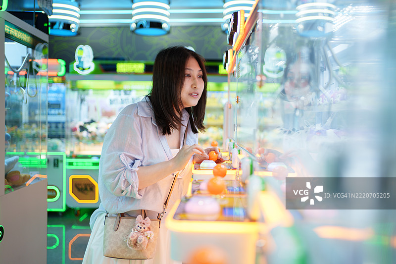 亚洲女性在玩抓娃娃机图片素材