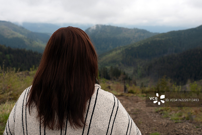 一位女性在山脉背景下的肖像。乌克兰喀尔巴阡山脉。年轻女性与自然的联系。心理健康。孤独。旅行。露营。山林旅游。图片素材