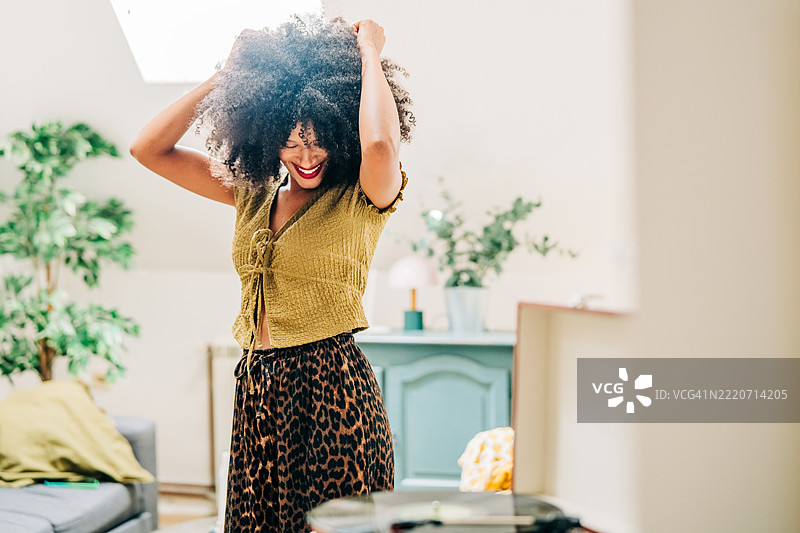 年轻女性在家中听着唱片机跳舞。图片素材