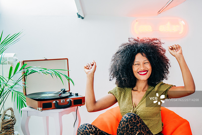 年轻女性在家中听着唱片机跳舞。图片素材