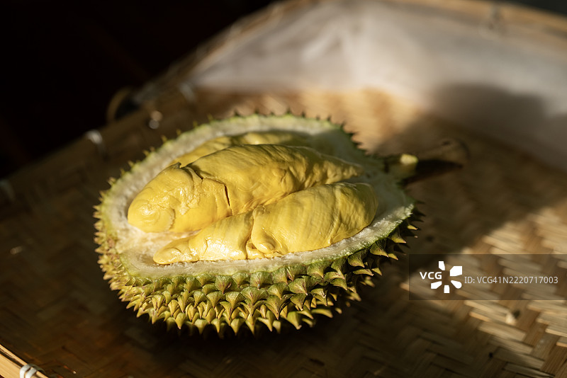 侧面视图的榴莲在桌子上打开，窗外的侧光照射，留有空白空间。图片素材