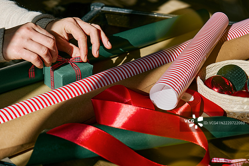 一个无法辨认的女性在圣诞树旁包裹圣诞礼物。冬季节日庆祝活动。图片素材