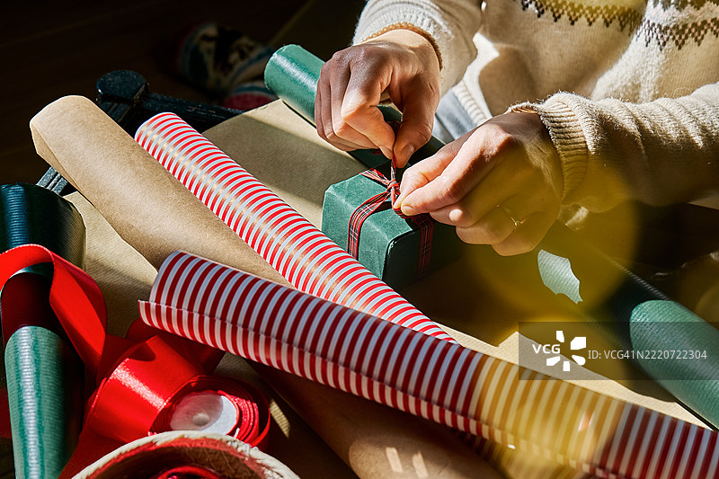 一个无法辨认的女性在圣诞树旁包裹圣诞礼物。冬季节日庆祝活动。图片素材