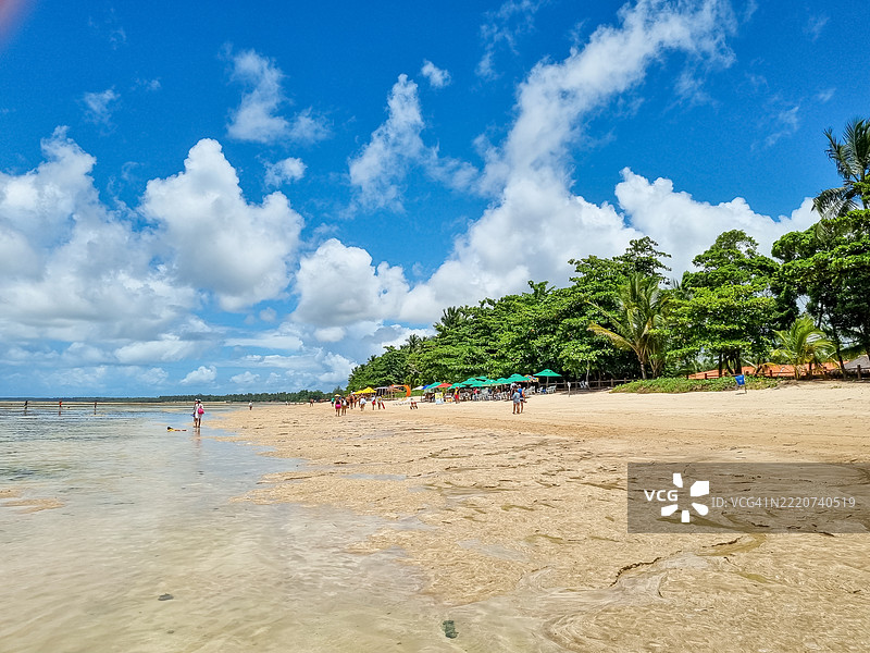 阳光普照的热带海滩，位于圣保罗角，碧蓝的海浪、金色的沙滩和郁郁葱葱的绿植勾勒出一个宁静而简单快乐的完美日子。图片素材