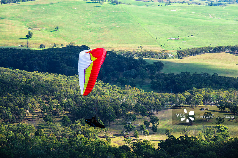 高角度视图下的人在风景上滑翔伞飞行图片素材