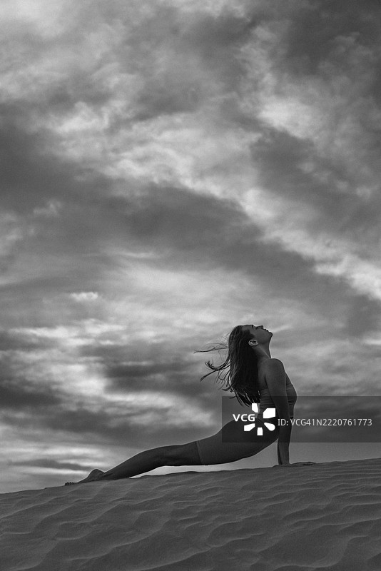 在多云的天空下，练习瑜伽的女性单色剪影图片素材