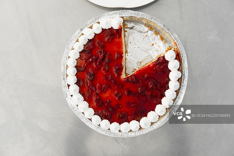 美味的草莓奶酪蛋糕，上面有鲜奶油，缺少两片。图片素材