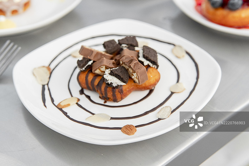 美味的甜甜圈，上面有巧克力和饼干的配料，点缀着杏仁和巧克力糖浆。图片素材