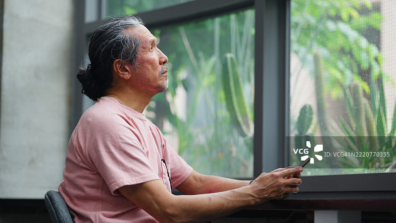 老年男子在现代建筑中使用智能手机的肖像图片素材