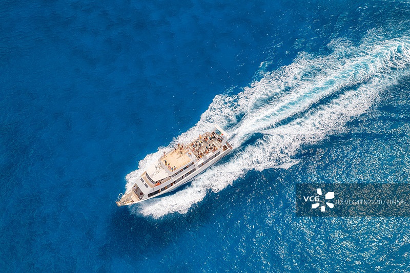 阳光明媚的日子里，蓝色海洋上美丽的漂浮游艇的鸟瞰图图片素材