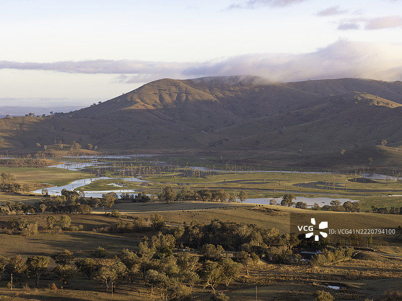 山谷、枯树和晨光中的蜿蜒河流图片素材