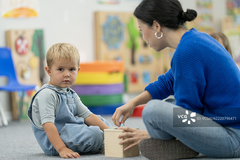 年轻儿童与教师在多彩的学习环境中互动图片素材