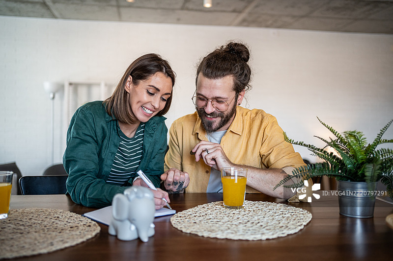 年轻夫妇在家计算家庭账单并微笑图片素材