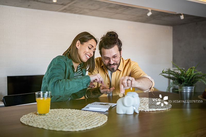 年轻情侣在家用储蓄罐存钱图片素材