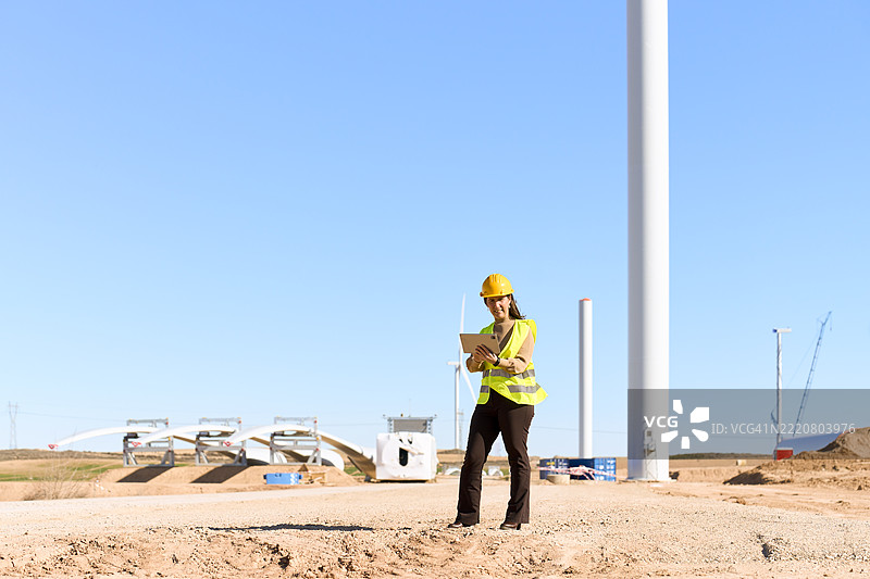 女性工程师在风力发电厂施工现场使用数字平板电脑图片素材