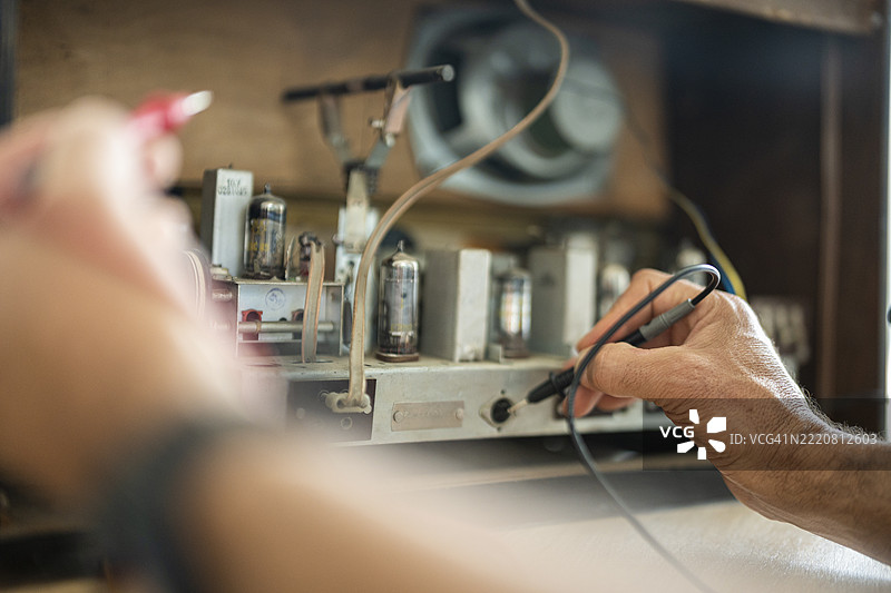 男人用万用表修理复古收音机图片素材