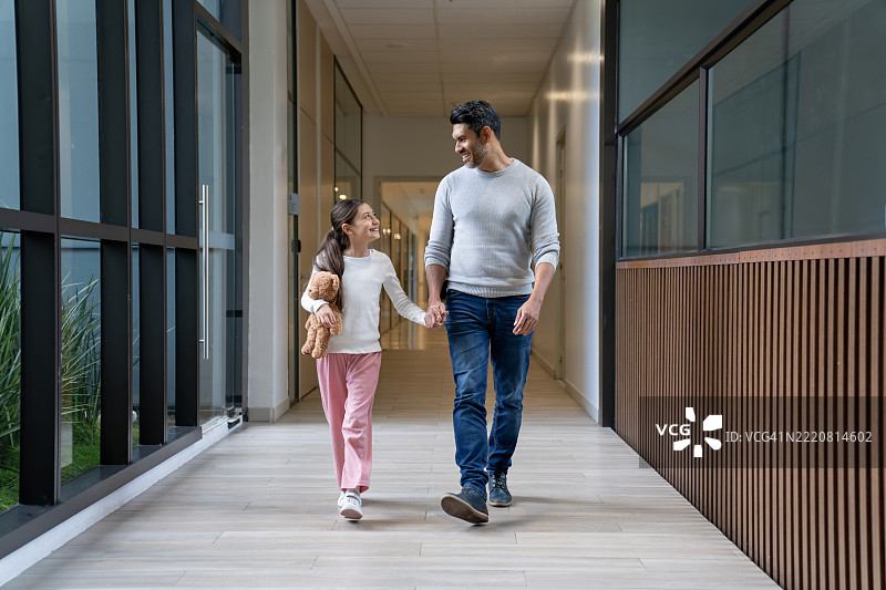 父亲和女儿在医院走廊里牵手行走图片素材